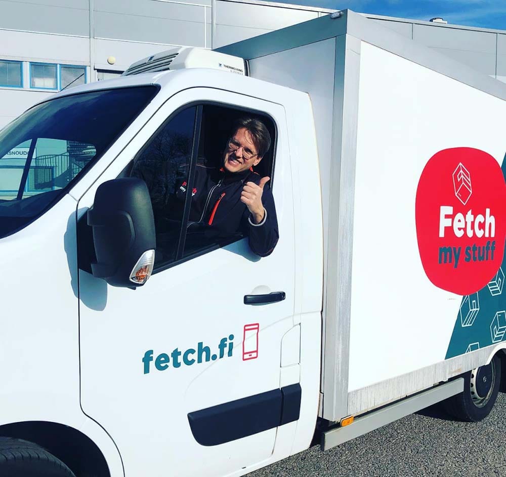 Hymyilevä Fetch-kuljettaja näyttää peukkua pakettiauton ikkunasta