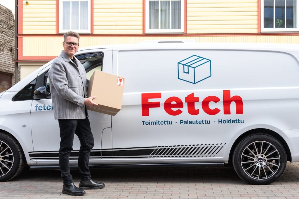 Asiakas paketti sylissään Fetch-pakettiauton vieressä
