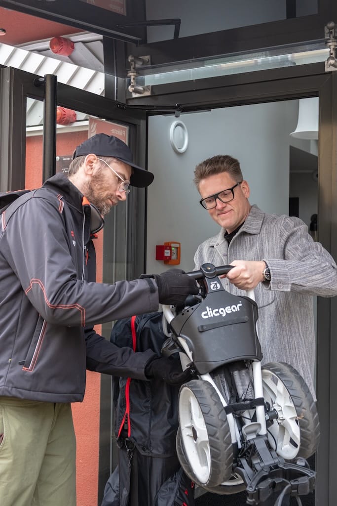 Fetch-kuljettaja luovuttaa golfkärryn asiakkaalle ovella